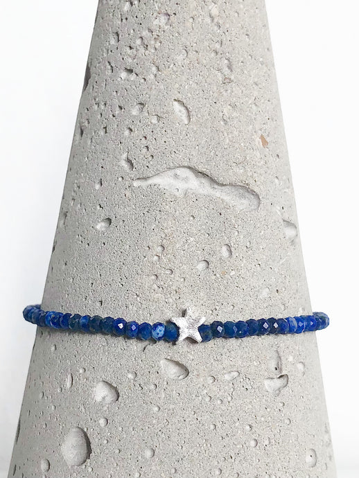 Armband aus facettierten Lapislazuli-Perlen mit Stern und diamantierter Kugel aus Sterlingsilber - Detailansicht auf Betonkegel.
