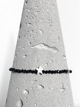 Lade das Bild in den Galerie-Viewer, Zartes Armband aus facettierten Spinellperlen in Begleitung eines silbernen Sterns &amp; einer diamantierten Kugel aus Echtsilber - Detailansicht auf Betonkegel.

