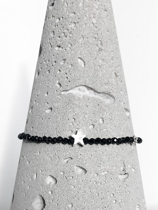 Zartes Armband aus facettierten Spinellperlen in Begleitung eines silbernen Sterns & einer diamantierten Kugel aus Echtsilber - Detailansicht auf Betonkegel.